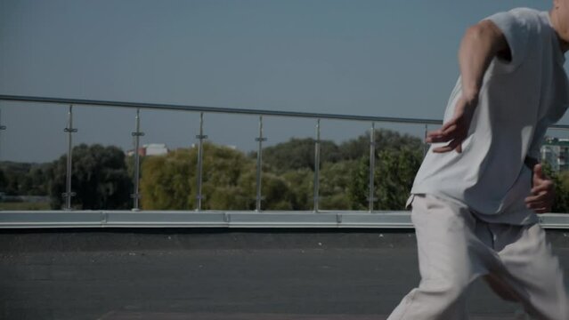 The guy coolly dances breakdance on the roof of the house. A man dances an energetic athletic dance.	
