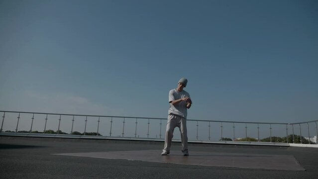The guy coolly dances breakdance on the roof of the house. A man dances an energetic athletic dance.	
