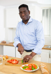 Man prepares a vegetable salad in the kitchen