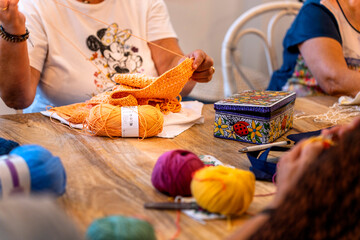 Crochet Club. Elderly women friends knitting together in a club. Colored wool on the table.