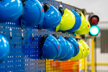 safety helmets of different colors on a rack in a factory, the concept of safety against injuries...