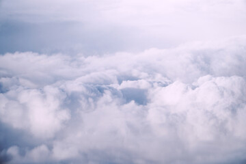 Aerial view White clouds in blue sky. Top. View from airplane. Aerial bird's eye. Aerial top view cloudscape. Texture of clouds. View from above. Sunrise or sunset over clouds