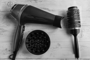 Photo of a black hairdryer with attachments and a comb on a wooden background