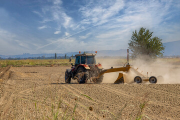 Obraz premium The farmer is preparing his field for planting with a tractor. He clears his field and plows it.