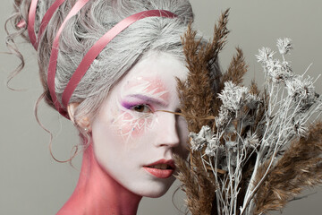 Sensual woman fashion model with carnival winter makeup and natural dried plant with snow