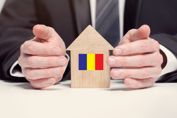 Businessman hand holding wooden home model with Romanian flag. insurance and property concepts