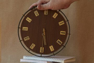 Large old clocks with Roman numerals stand on notebooks and organizers. Passage of time, work and...