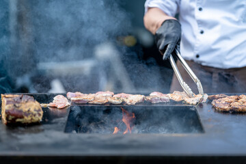 grilling meat for catering on an outdoor grill with an open fire, food street