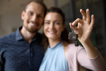 Smiling happy young married couple holding keys from new home, symbol real estate property buying, new apartment rent, housing, becoming homeowners, celebrating ownership, achievement - obrazy, fototapety, plakaty