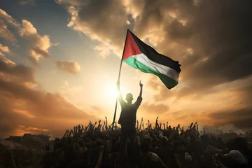 Fotobehang Silhouette of a Palestinian man waving Palestine flag over people. © ZayNyi