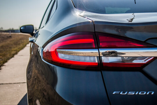 Red and white taillight of a black Ford Fusion car