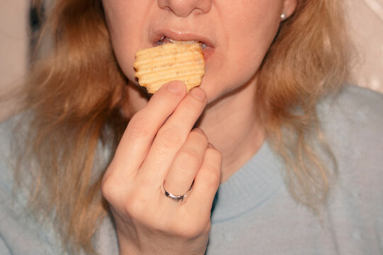 woman's mouth biting into a fried potato.
