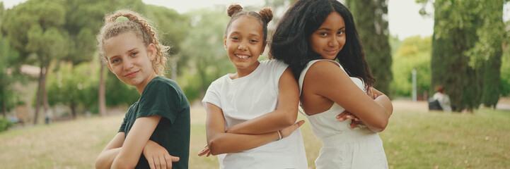 Smiling three girls friends pre-teenage cross their arms in dance move in the park