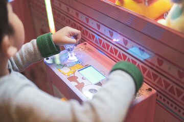 Kid holding joystick. kid play in the arcade center of the machine to get the claws of soft toys.