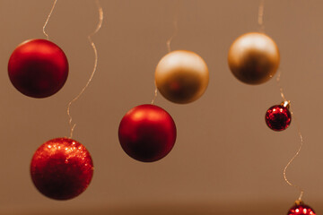 Naklejka na ściany i meble Christmas golden red glossy balls hanging in the interior on beige background. New Year details and festive atmosphere