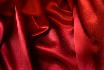 Red silk satin abstract background. Beautiful soft wavy folds on smooth luxury shiny fabric with...