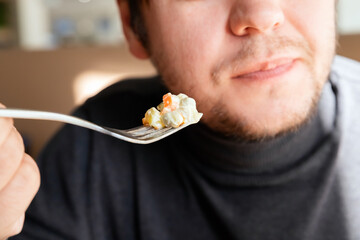 Male man eating russian Olivier salad with meat, vegetables and mayonnaise. Traditional russian...