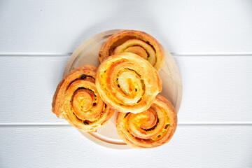 fresh ruddy hot breakfast baking pastries with a crispy crust and sweet filling from the bakery in white paper on wooden table on white background. Top view