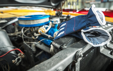 Fototapeta na wymiar Protection Gloves Laying Next to Classic Car Engine Compartment