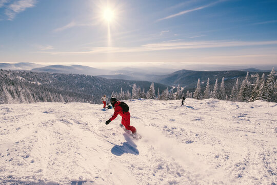 Woman riding  snowboard on  sunny snowy slope with beautiful mountain valley view. Sports outdoor lifestyle
