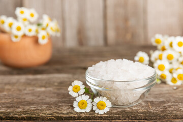 Spa sea salt on texture background. Sea salt with chamomile extract in a glass jar on the table. Beauty concept. Sea bath salt. Place for text, copy space.Close-up.