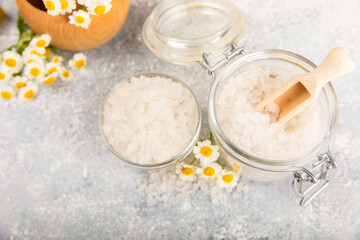 Spa sea salt on texture background. Sea salt with chamomile extract in a glass jar on the table. Beauty concept. Sea bath salt. Place for text, copy space.Close-up.
