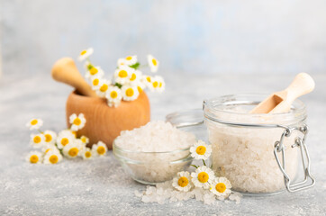 Spa sea salt on texture background. Sea salt with chamomile extract in a glass jar on the table. Beauty concept. Sea bath salt. Place for text, copy space.Close-up.