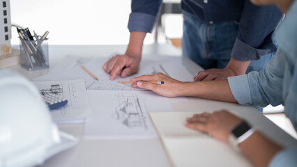 Two engineer architect discussion and inspecting sketching about interior architectural building on blueprint to analysis technical for construction plan while working together in workplace site