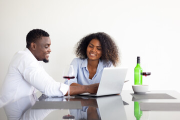 Couple using laptop computer in kitchen at home. Happy excited successful African American man and woman couple togetherness at home office. Work from home