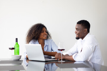 Happy excited successful African American man and woman couple togetherness at home office. Work from home. Couple using laptop computer in kitchen at home