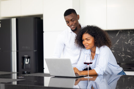 Happy Excited Successful African American Man And Woman Couple Togetherness At Home Office. Work From Home. Couple Using Laptop Computer In Kitchen At Home