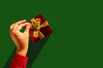 Unwrapping Joy: Woman's Hand Reveals the Magic Inside the Golden-Glazed Gift. Christmas background