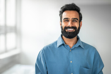 Male entrepreneurship. Closeup portrait of indian bearded businessman smiling at camera in office, copy space