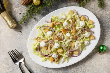 Christmas appetizer. Christmas New Year salad chinese cabbage, feta cheese, chicken and croutons on the festive table. View from above.