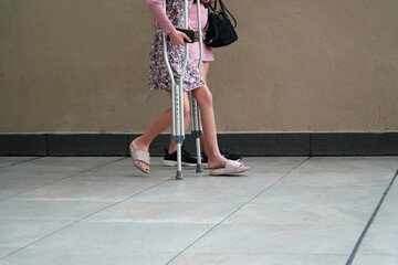 girl walking with crutches with his mom