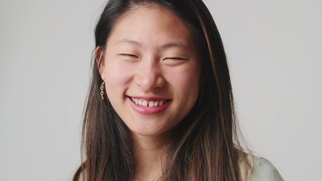 Close up, young woman looking at camera smiling and laughing isolated over white background in studio