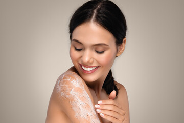 Positive young caucasian lady with perfect skin applies cream to shoulder enjoy hygiene, shower