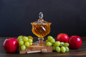 Fresh honey and fresh fruits for Jewish holiday Rosh Hashanah on dark background.
