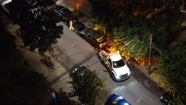 Car being towed in Brooklyn at night