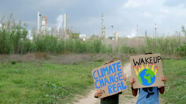 Young activists rally outside a polluting factory, holding signs against pollution, global warming, and advocating for ecological awareness and a hopeful future. Factories emit CO2 and toxic smoke.