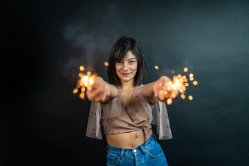 Happy beautiful woman holding festive sparkler among Christmas night