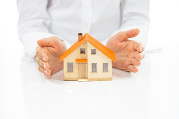 Close-up of woman's hands holding a small model house.