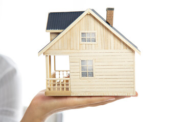 Close-up of woman's hands holding a small model house. 