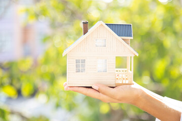 Close-up of woman's hands holding a small model house.