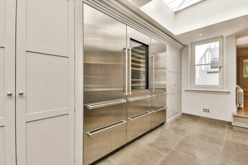 a modern kitchen with stainless steel appliances and white cupboards, in an open space that is well lit by the skylight