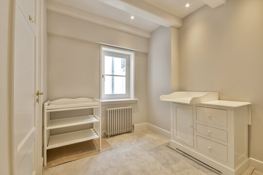 a baby's room with a cribt, dresser and changing table in the wall is painted white
