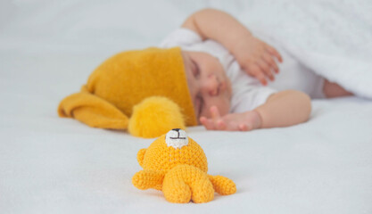 Sleeping child in bed holding teddy bear.