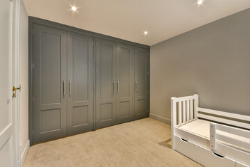 a baby's room with grey walls and white cribts on the floor in front of the bed