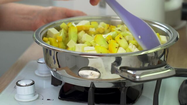 A woman mixes feta cheese with zucchini in a saucepan while cooking. Close-up. Diet dish.