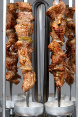 Cooking pork meat in an electric kebab maker on vertical skewers